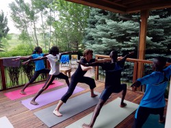 Uta is helping the athletes to get into Warrior Two pose. © Take The Magic Step