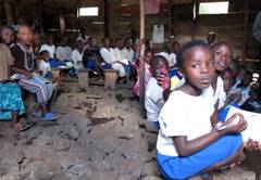 School kids have no desks, and sit on rocks while attending class. © Courtesy of PeopleWeaver